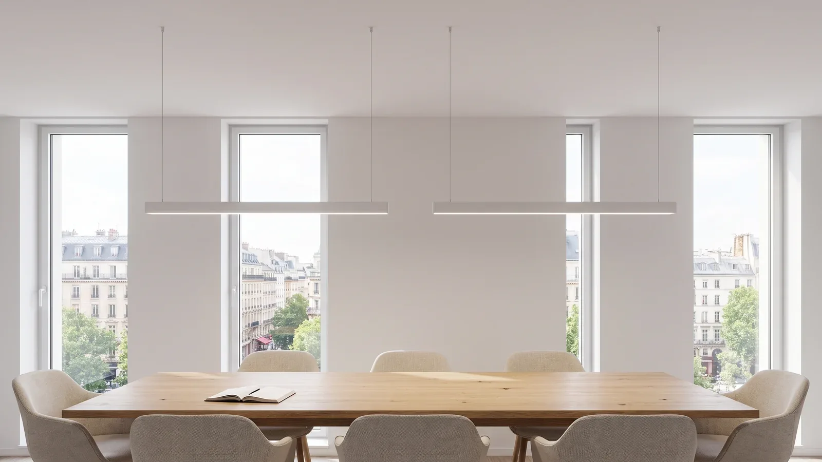 Sala de reuniones contemporánea con luminarias lineales blancas suspendidas de cables finos sobre una mesa de roble.